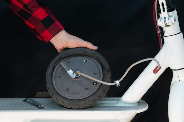 Reparatie van elektrische scooters In de handen van de meester een wiel van een scooter met een lekke band Vervanging van banden en tuby in de werkplaats