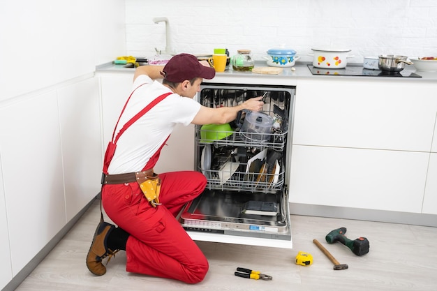 Reparatie van vaatwassers. De meester is thuisgekomen en repareert de vaatwasser.