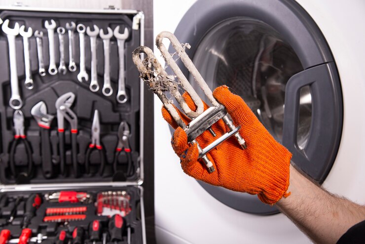 Reparatie van wasmachines. Hand van een reparateur met een turbulente elektrische kachel bedekt met een laag hard water.