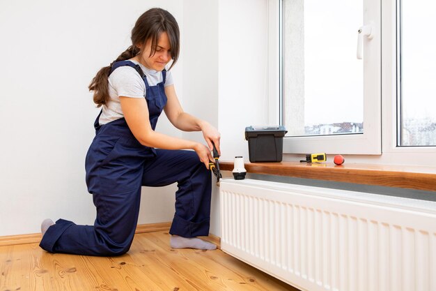 Reparatie verwarmingsradiator close-up vrouw die radiator met moersleutel repareert