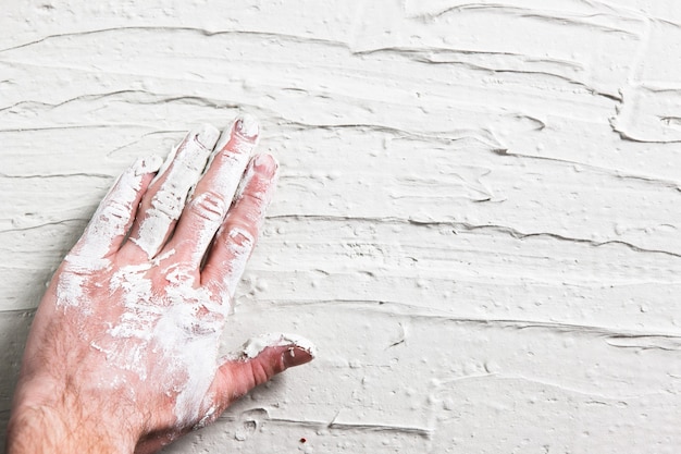 Reparatieachtergrond, plat leggen van witte gipsmuur met arbeidershand. Ruwe grungy achtergrond met vrije ruimte voor tekst.