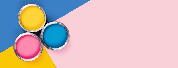 Repare web-banner tricolor blue yellow pink background with three colors paint cans flat lay top view copy space