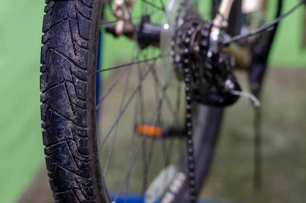 Repareer mountainbike in de werkplaats Een oude roestige ketting vervangen door een nieuwe Hulpmiddel voor het verwijderen en installeren van kettingen close-up Groene achtergrond