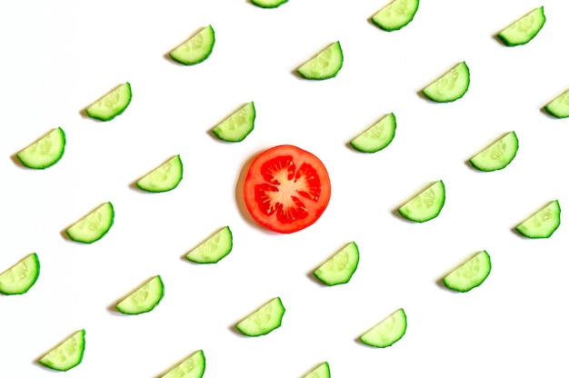 Repeating pattern of sliced semicircles of fresh raw vegetable cucumbers for salad and a tomato