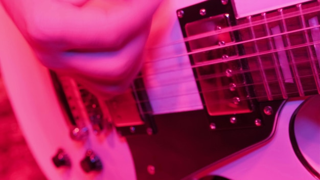 ロック音楽バンドの繰り返し赤い光の中でエレクトリック ギター プレーヤーのトリミングされた画像