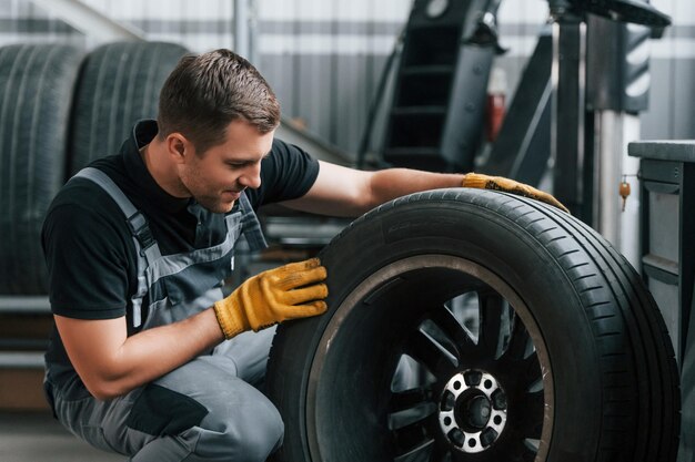 Replacement of the old tire man in uniform is working in the\
auto service