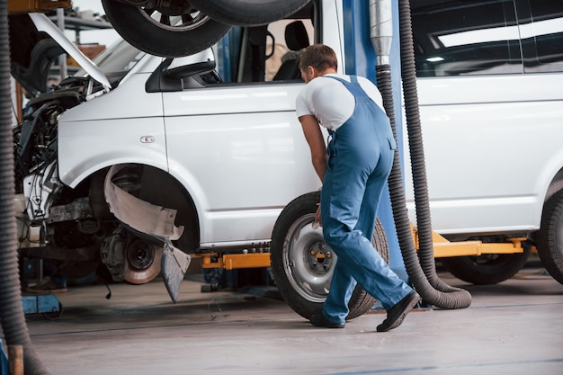 Replacement of tyres. Employee in the blue colored uniform works in the automobile salon