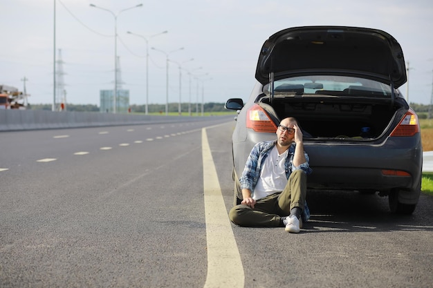 道路上の車のホイールを交換します。傍観者のタイヤ仕事をしている男。