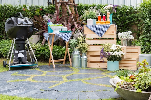 A replica of barbecue and black grill with seasoning set on wooden boxs in the garden