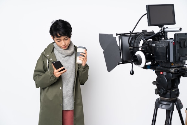 Reporter Vietnamese woman holding a microphone and reporting news holding coffee to take away and a mobile