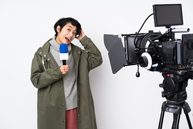 Reporter Vietnamese woman holding a microphone and reporting news surprised and pointing finger to the side