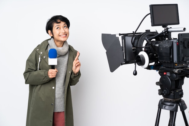 Reporter Vietnamese woman holding a microphone and reporting news with fingers crossing