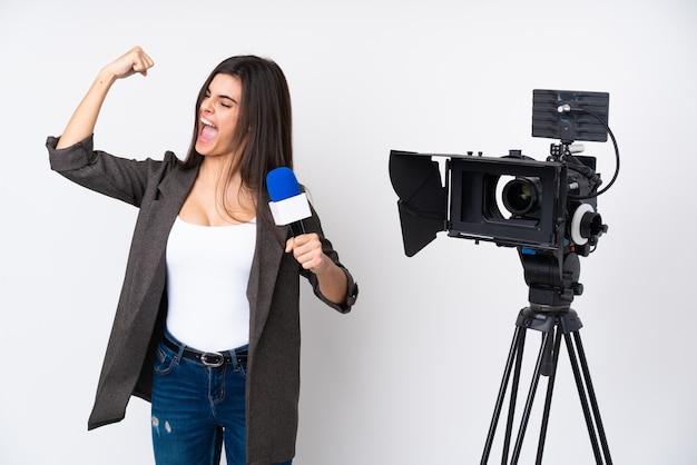 Женщина репортера держа микрофон и сообщая новости над изолированной белой стеной празднуя победу