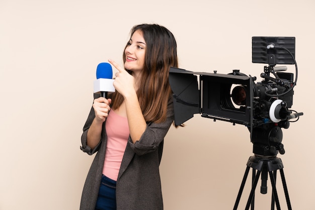 Reporter woman holding a microphone and reporting news over wall pointing with the index finger a great idea