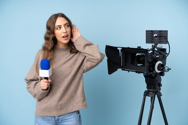 Reporter young woman holding a microphone and reporting news listening something