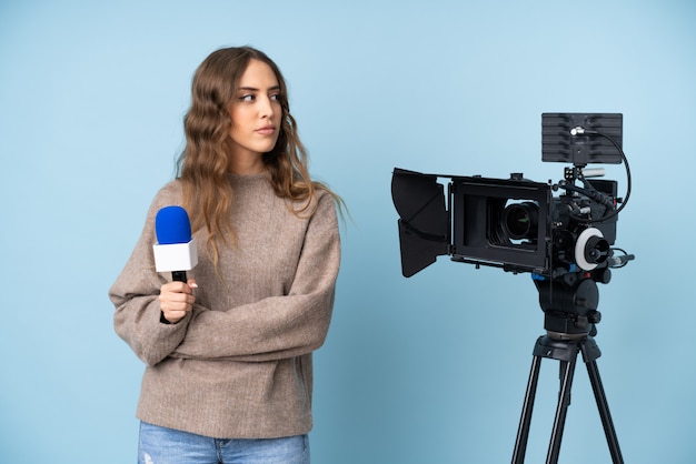 Reporter young woman holding a microphone and reporting news looking side