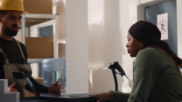 repository warehouse director carrying out the logistics of receiving processing storing and sending inventory according to purchase orders and shipping schedules helped by african american woman