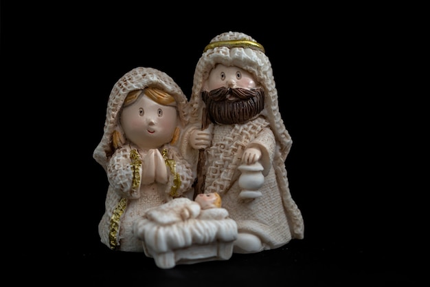 Rappresentazione di un presepe di natale con le piccole figure di gesù bambino, maria e giuseppe su sfondo nero. concetto di natale.