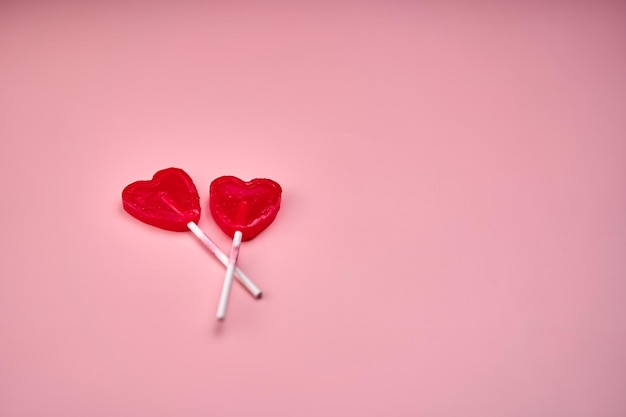 Representation of love through two heartshaped lollipops on a pink background