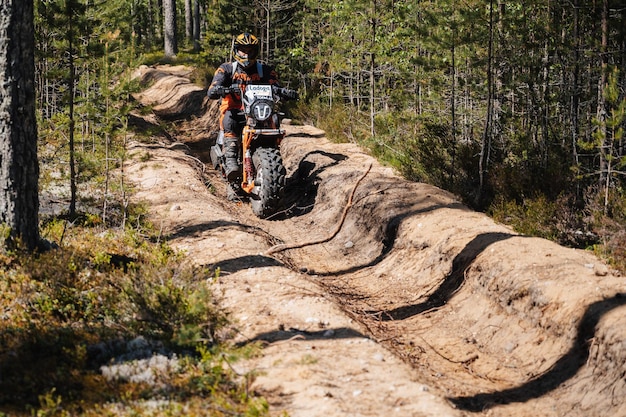 Photo republic of karelia russia circa june 2022 offroad tournament ladoga trophy 2022 in karelia motorcyclist rider on sports motorcycle rides fast on a dusty road in forest in motocross race