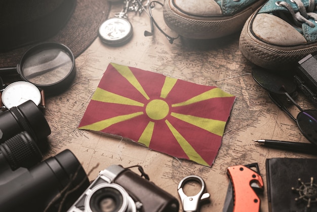 古いビンテージマップ上の旅行者のアクセサリーの間にマケドニア共和国の旗。観光地のコンセプト。
