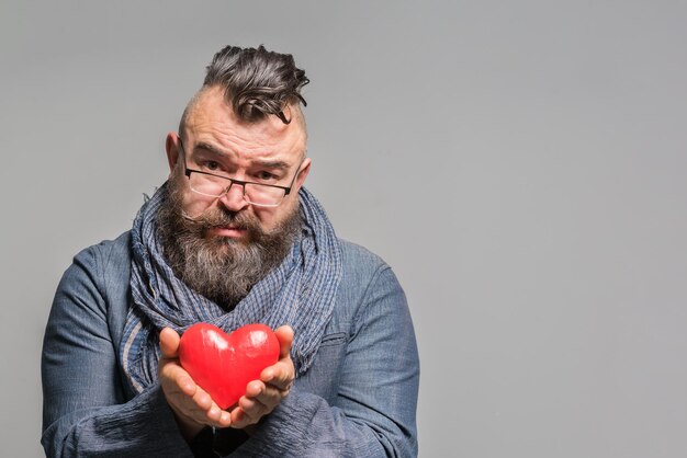 Photo requesting bearded man in a blue jacket and scarf holding red heart