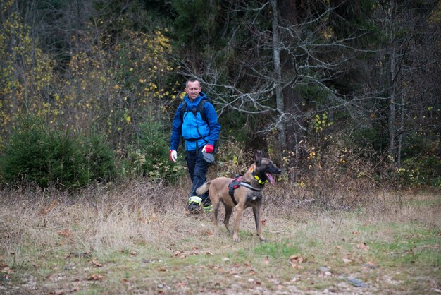 Rescuer and dog inspecting woods searching missing person