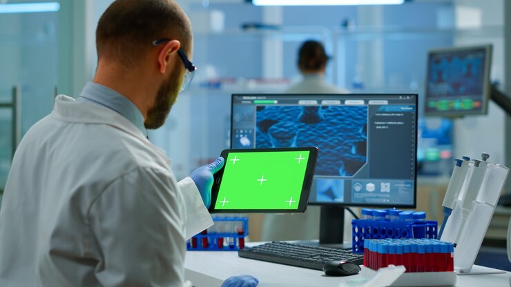 Photo researcher holding and looking at tablet with chroma key display in modern equipped lab. team of microbiologists doing vaccine research writing on device with green screen, isolated, mockup display.