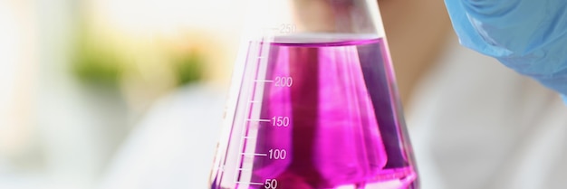 Researcher holds flask of purple liquid with gloves household liquid research concept