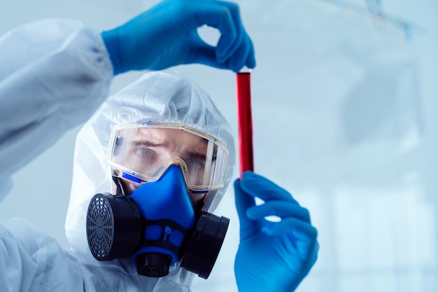 Researcher is looking at the red liquid in the bottle