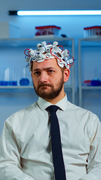 Photo researcher neurologist doctor asking man's symptoms taking notes on clipboard before brain scan with brainwave scanning headset