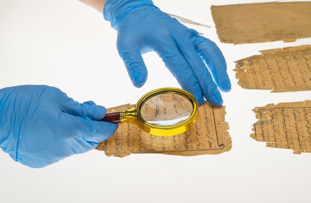 Foto il ricercatore studia la scrittura araba del corano usando una lente d'ingrandimento e un tavolo con una luce