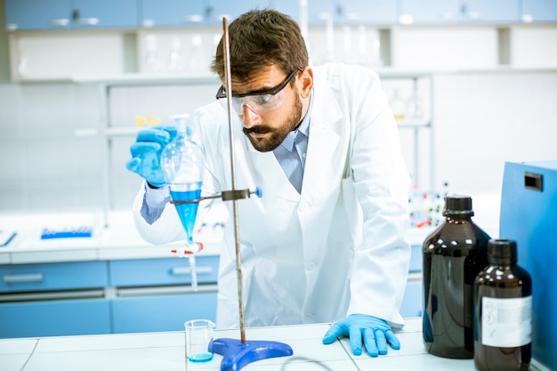 Photo researcher working with blue liquid at separatory funnel in the laboratory