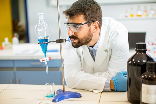 Photo researcher working with blue liquid at separatory funnel in the laboratory