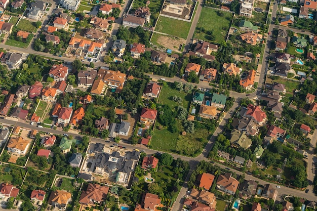 Residential area rooftops view from a drone cottages in the
village land view through the airplane window look out the window
of a flying plane top view of the ground