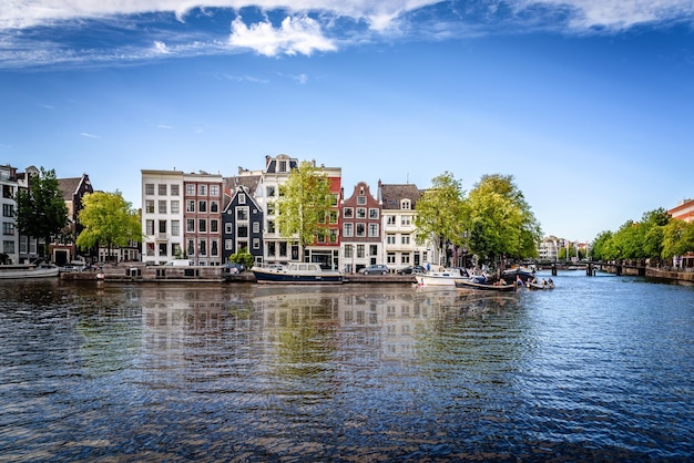 Residential buildings in city by canal against blue sky
