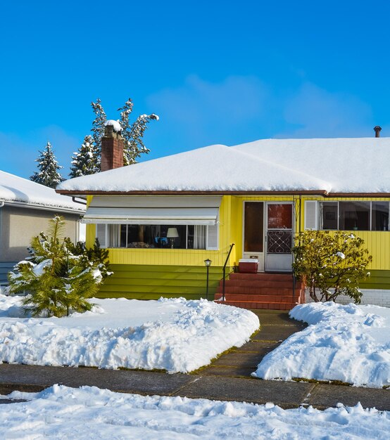 Residential house in snow on a sunny day on blue sky background