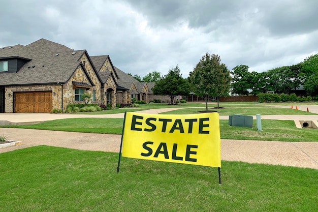 Residential house with road and neat lawn in front big yellow sign with estate sale inscription