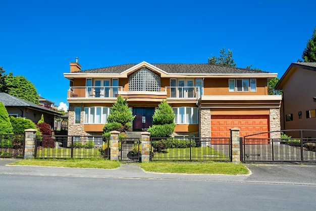 Residential house with wide garage landscaped yard and metal fence in front