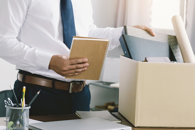 Resignation businessman packing personal company belongings in a brown cardboard box