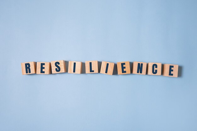 Resilience word concept on cubes on blue background.