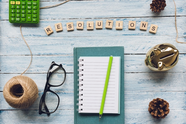 RESOLUTIONS word and a notepad on light blue wood