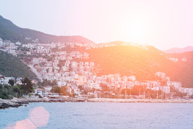 Resort town on a rocky beach by the sea with a pier for boats in the sunlight