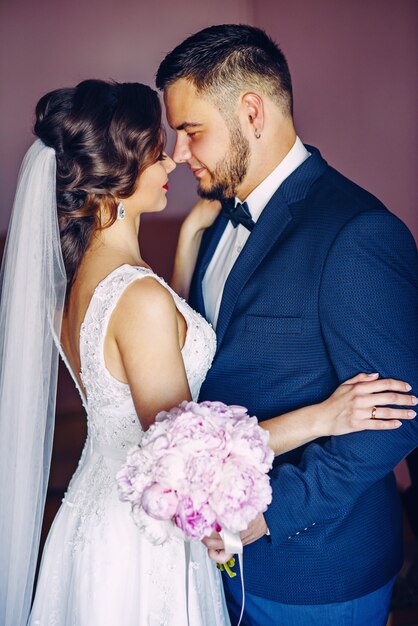 Respectable groom hugging his sensual bride at the room.