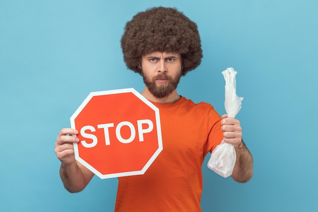 Responsible man holding red stop sign and plastic package looking at camera