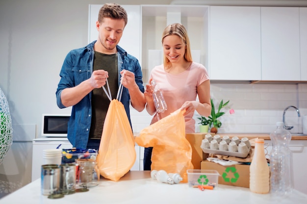 Responsible young family putting empty plastic and paper in bags