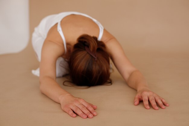 Rest after an intense yoga workout. woman in white clothes on a beige background. international yoga day