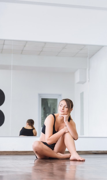 Rest between exercises. Cute attractive skillful woman sitting on the floor and leaning on her leg while resting during her workout