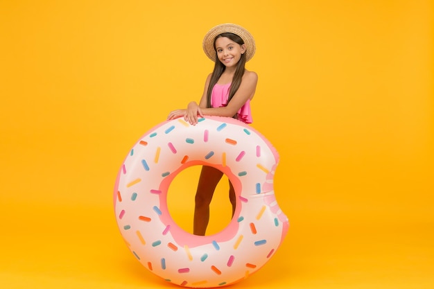 Rest at seaside. Pool party. Happy childhood. Entertainment concept. Little girl and swimming donut ring. Kid in swimsuit having fun water activities. Swimming and sunbathing. Summer vacation.