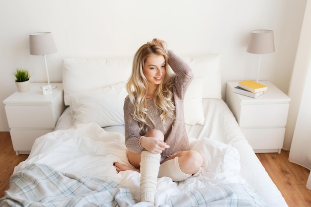 rest, sleeping, comfort and people concept - happy young woman posing in bed at home bedroom